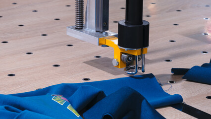 Aufkleber - A blue shirt is being sewn by a machine. The machine is black and yellow