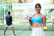 © JackF - Positive girl looking at camera while playing padel at court outdoor