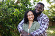 © Wavebreak Media - Happy multiracial couple embracing outdoors, smiling warmly in lush green garden