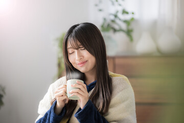 Poster - 冬のリビングで温かい飲み物を飲むくつろぐ目を閉じる若い女性