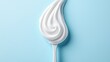 © Alpha - Toothbrush standing upright with a toothpaste swirl perfectly balanced on its bristles, captured in a detailed close-up on a soft blue background