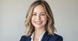 © Surachetsh - A confident blonde businesswoman in a blue suit beams warmly against a clean blue background, highlighting her professional image.