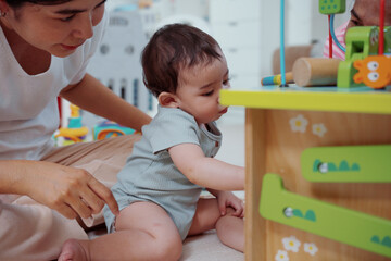 Cute Asian woman and little son playing educational toys together in living room. Mom and son play cubes and laugh Happy family. Young mother and son doing activities together at home.