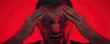 © Thamonchanok - Man in distress expressing intense emotions against a vibrant red background.