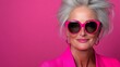 © Nataliia_Trushchenko - Woman in a pink suit and sunglasses. She is smiling and looking at the camera. The pink background and the sunglasses give the image a fun and playful mood