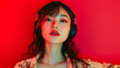 © ki - Stylish young Chinese woman and man wearing headphones, enjoying music in a vibrant red neon studio background, capturing the essence of modern youth culture and creativity.