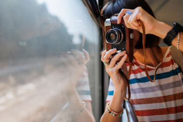 train travel. Young woman enjoying a train ride with a camera. tourist takes pictures of beautiful tourist places on camera. film camera.