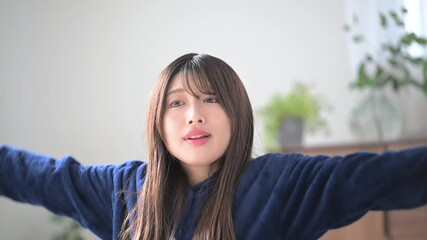 Poster - 部屋に座って伸びをする、起床する若い女性　秋冬の朝のリラックスのパジャマの上半身の目を閉じる正面の動画