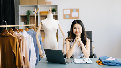 fashion designer. Attractive woman with smile while standing in workshop. Beautiful owner woman working and holds tablet, laptop and smartphone in studio.