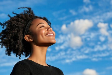 Joyful young black woman embracing life under a bright blue sky