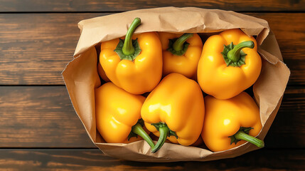 Wall Mural - Top view of a paper bag filled with fresh yellow bell peppers on a wooden table surface, showcasing vibrant colors and organic produce.