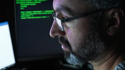 A software developer writing code in close-up. Hacker, cyber security, penetration testing concept. Screen light and computer code reflecting on his face. System administrator. 4K Resolution.