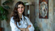 © Mahemud - Portrait of a brunette young medical doctor with a stethoscope, smiling at the camera with arms crossed.