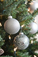 Closeup photo of a Christmas pine tree with sparkly silver Christmas baubles, Christmas lights 