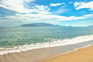 Nha Trang city, Vietnam - October 29, 2024 : Overlooking the beautiful coast of Nha Trang with palm trees on the beach with deck chair and parasol. Beautiful white sand tropical beach in coastal city.