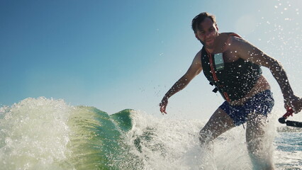 A novice athlete falls from a wakeboard while riding at high speed. Water sprays up, showing a moment of loss of balance and adrenaline. The scene reflects the risk and dynamics of water extreme sport