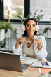 © Bliss - A young beautiful woman smiles warmly while working at her desk, surrounded by greenery.