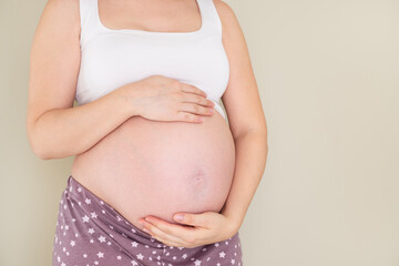 Pregnant woman holds hands on belly touching her baby caring about her health