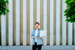 © Iryna - Confident man with laptop outdoors against modern concrete wall