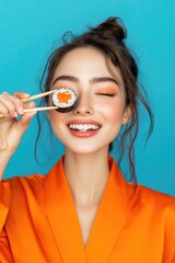 A woman is seen wearing an orange robe and holding chopsticks to her eye, a unique and quirky pose