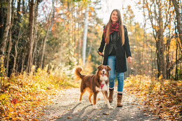 Loving young woman with her shepherd Australian on fall season