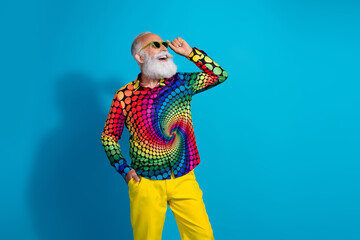 Photo of eccentric funky aged man touch sunglass empty space wear shirt isolated on blue color background