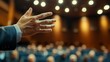 © Pumapala - A speaker gestures toward an audience in a conference setting, emphasizing engagement.