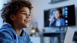 © vefimov - A cheerful young boy engrossed in watching a video on his laptop, with a television screen reflecting the content he is enjoying.