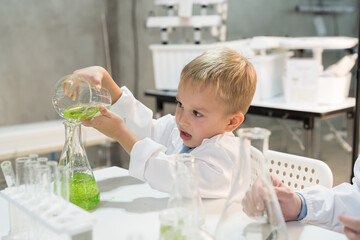 Little child boy scientists learning science and doing analysis with glassware, liquid and tube in laboratory. Scientific experiment and Research. Early development of children