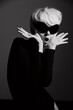 © SHOTPRIME STUDIO - Surprised woman with short blonde hair and oversized sunglasses posing dramatically in a chic black outfit against a dark background. Fashion and style concept.