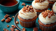 © El_design - Homemade pumpkin spice caramel pecan cupcakes with cream cheese frosting and tea on a soft turquoise stone tabletop.