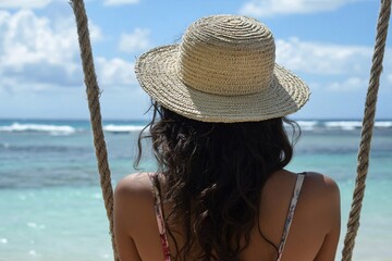 A young Mauritian woman in a straw hat, sitting on a swing overlooking the ocean, relaxed, sunny day 2