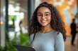 © Maelgoa - A young businesswoman smiling confidently while holding a tablet, against a modern office backdrop with clean lines 3