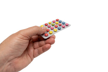 A man holds a package with multi-colored pills inside. Tablets of different colors. Health and wellness concept.