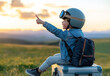 © Quality One   - child in pilot helmet and goggles sits on suitcase, pointing towards sky during sunset. scene captures sense of adventure and imagination