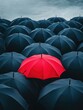 © vefimov - A single red umbrella stands out in a sea of black ones on a rainy day.