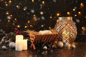 Manger with baby, fir branches, burning candles and glowing lights on dark background. Christmas story concept