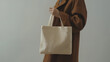 © VikaKa - High-quality photo of a woman holding a blank canvas fabric tote bag, ideal for mockup or branding template