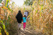 © Anya Brewley Schultheiss/Stocksy - A group of young sisters walking in a corn maze, surrounded by stalks