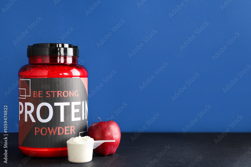 Bottle with protein powder, scoop and apple on table against color background
