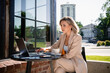 © DZ FILM/Stocksy - A woman uses a laptop sitting on a cafe terrace