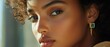© BloomArt - Close up portrait of a beautiful woman with curly hair wearing gold earrings with emerald stones.