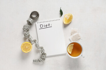 Wall Mural - Notebook with word DIET, cup of tea, lemon and measuring tape on light background. Weight loss concept
