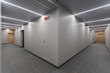 © alhim - The corridor of a commercial building with light walls, gray floor tiles and brown doors..