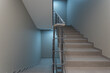 © alhim - A corridor with light walls, beige floor tiles and a staircase with metal railings.