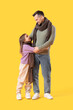 © Pixel-Shot - Happy father and his daughter in sweaters hugging on yellow background