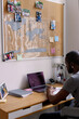 © Oleksii Syrotkin/Stocksy - Adult black man watching laptop in chair at desk with open copybook