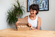 © Alvaro Lavin/Stocksy - Woman smiling and opening a box of wooden pawns for board game