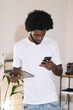 © Guille Faingold/Stocksy - Afro casual businessman holding a tablet and phone in his hands