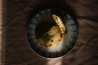 © Adrian Cotiga/Stocksy - Single cookie on ornate plate on a dark textured surface.
